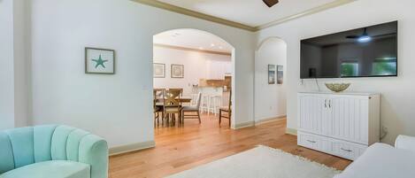 A living room with a ceiling fan, a TV, and a dining area with chairs and a table.
