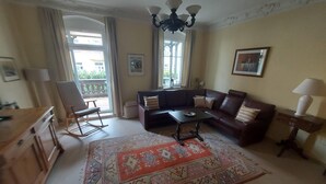 A living room with a sofa, a coffee table, a rug, a painting, and a chandelier.