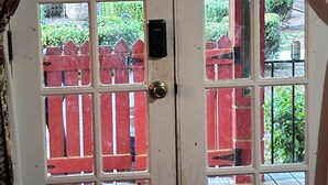 A white door with a glass panel, a red picket fence, and a wooden deck visible through the glass. - Charming 1-bedroom farm guesthouse in Lexington with WiFi and AC (Lexington)