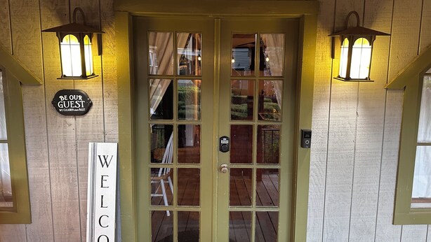 A wooden door with a sign reading "WELCOME" and two wall-mounted lanterns. - Charming 1-bedroom farm guesthouse in Lexington with WiFi and AC (Lexington)