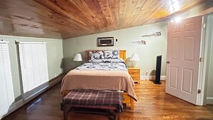 A bedroom with a wooden ceiling, a bed with a plaid blanket, two bedside lamps, and a door. - Charming 1-bedroom farm guesthouse in Lexington with WiFi and AC (Lexington)