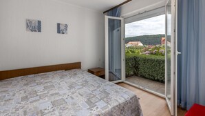 A bedroom with a bed, a small bedside table, a sliding glass door to a balcony, and two wall-mounted artworks. - 1 bedroom lovely apartment in Supetarska Draga (Supetarska Draga)