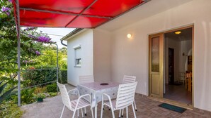 A patio with a table and chairs, a red canopy, and a door leading to an interior space. - 1 bedroom lovely apartment in Supetarska Draga (Supetarska Draga)