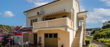A two-story house with a balcony, a satellite dish, and a staircase leading to the upper floor.