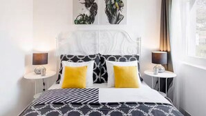 A modern bedroom with a black and white patterned bedspread, two yellow pillows, and a decorative headboard. - Gorgeous home in Mravince (Mravince)
