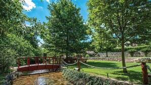 A park with a red bridge, stone walls, and picnic tables. - Gorgeous home in Mravince (Mravince)