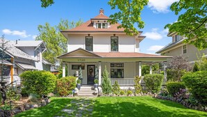 A two-story house with a front porch, a stone pathway, and a well-maintained lawn.