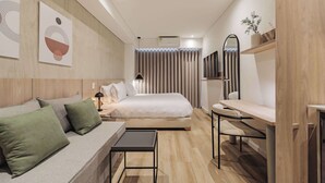 Una habitación de hotel moderna con cama, sofá, escritorio y televisor.