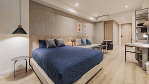 Un dormitorio moderno con una cama grande, mesitas de noche, un escritorio y una silla.