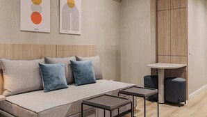 Un dormitorio moderno con un sofá, dos mesitas de noche y un armario.