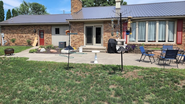 Ein Ziegelhaus mit Veranda, Grill und Gartenmöbeln.