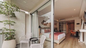 A modern hotel room with a large bed, a small table, and two chairs. There is a potted plant on the balcony. - Quadrato | Laureles Studio, w/AC, Balcony, WIFI (Medellín)