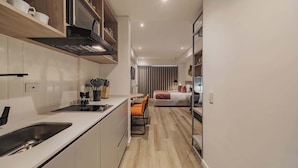 A compact, modern hotel room with a kitchenette, a bed, and a seating area. - Quadrato | Laureles Studio, w/AC, Balcony, WIFI (Medellín)
