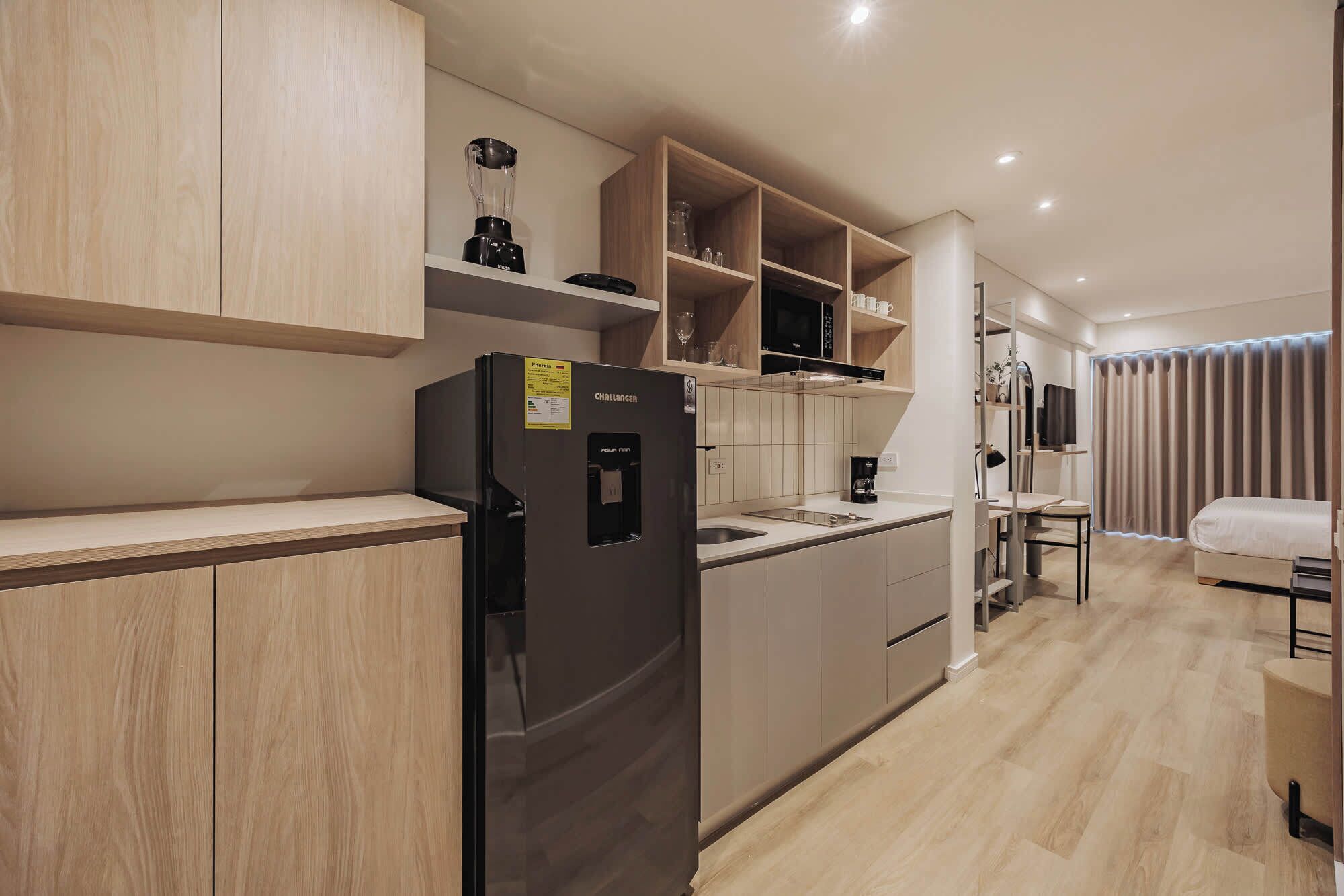 Una cocina moderna con armarios de madera, un refrigerador negro y un microondas empotrado.