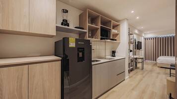 Una cocina moderna con armarios de madera, un refrigerador negro y un microondas empotrado.