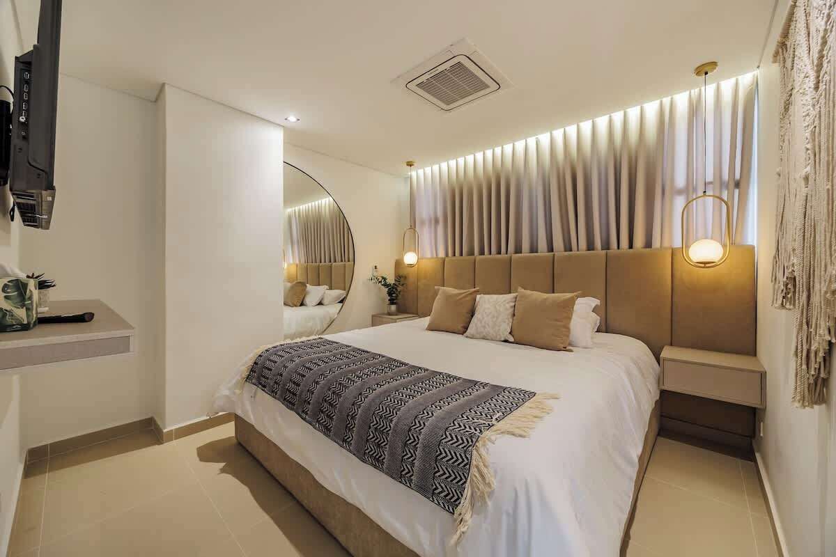 Une chambre moderne avec un grand lit, une table de chevet, un miroir et un luminaire fix é au mur.