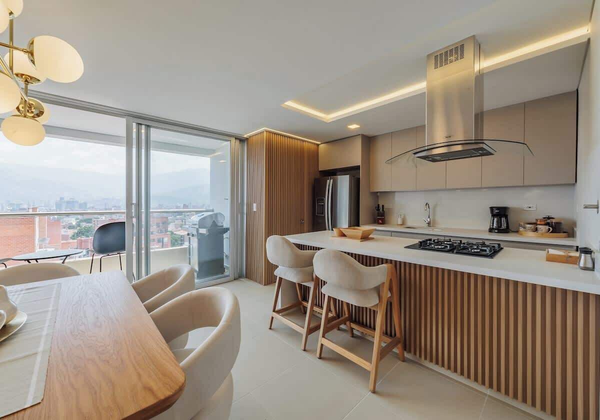 Une cuisine moderne dotée d’un îlot central, de tabourets de bar et d’un coin repas avec une table et des chaises.