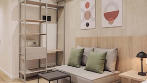 Un dormitorio moderno con armario empotrado, cama con almohadas verdes y grises, y dos piezas de arte abstracto en la pared.