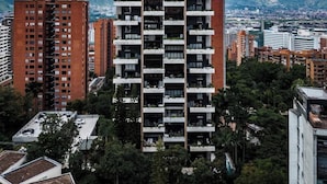 A high-rise building with a modern design, featuring multiple balconies and a prominent sign at the top.