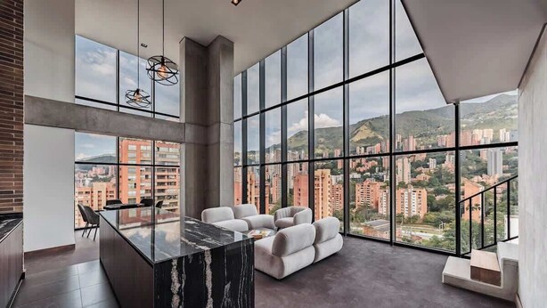 A spacious living area with a large window, a marble island, and a seating area.