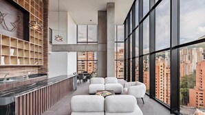 A modern interior with a kitchen area, seating, and large windows offering a city view.