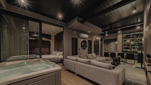 A modern living room with a large sofa, a hot tub, and a built-in entertainment system.