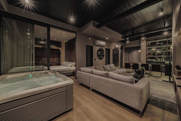 Una sala de estar moderna con un sofá grande, un jacuzzi y un sistema de entretenimiento integrado.