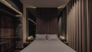 A modern hotel room with a large bed, wooden paneling, and two bedside lamps.