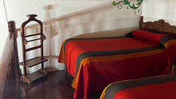 A room with two beds, wooden beams, a chandelier, and a decorative wall panel.