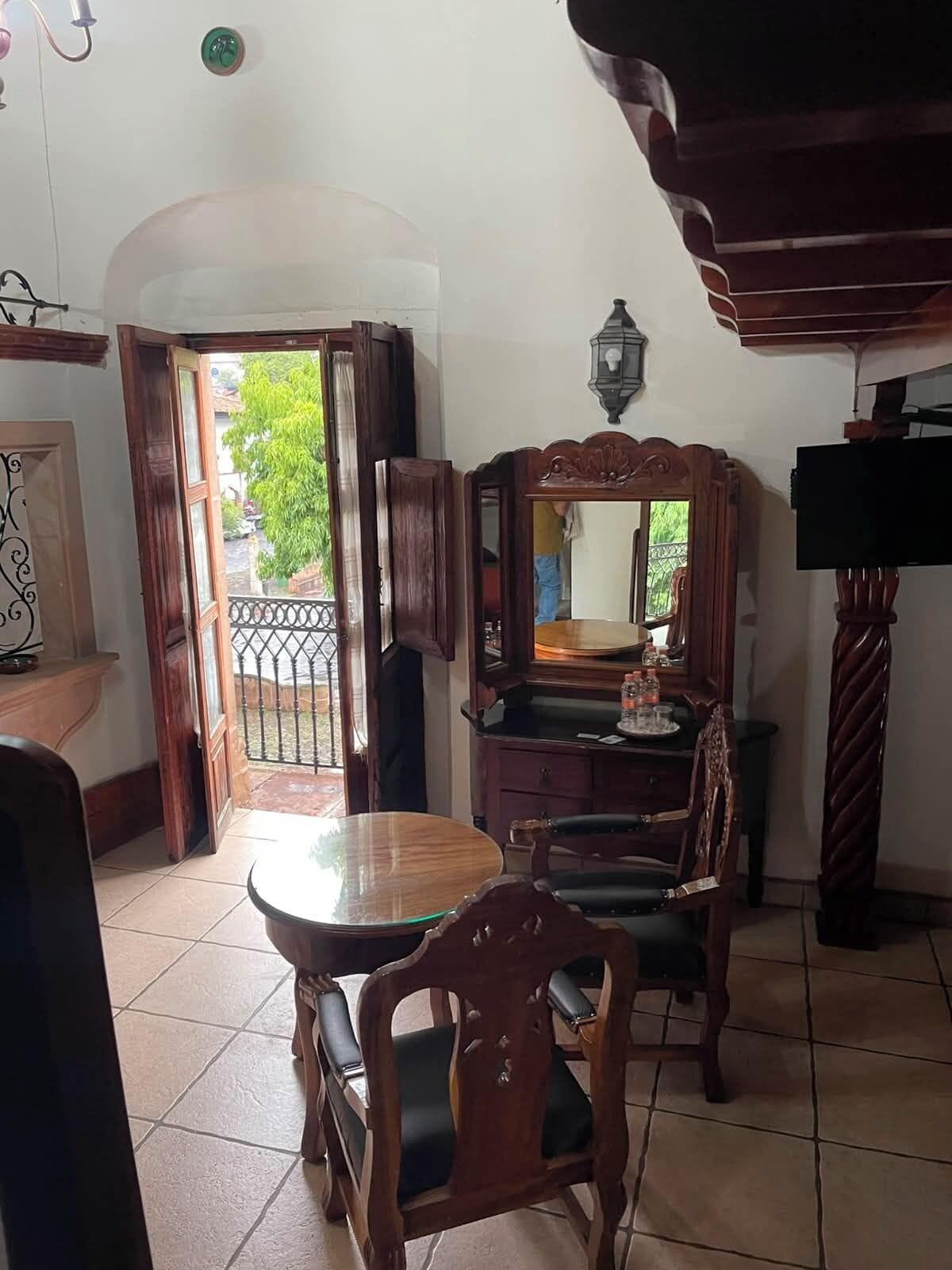 A dining area with a round table and chairs, a wooden cabinet, and a television.