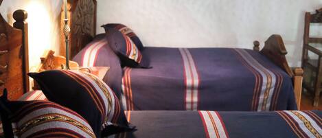 Una habitación con dos camas, una mesita de noche, una lámpara y una silla.