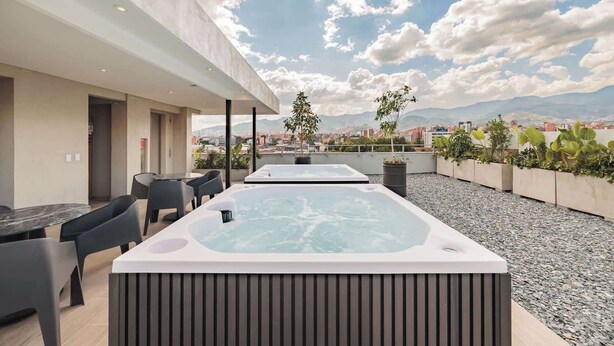 A rooftop terrace with two hot tubs, outdoor seating, and a city view. - Quadrato | Laureles Studio, w/AC, Balcony, WIFI (Medellín)