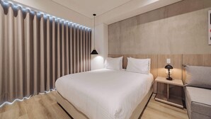 A modern hotel room with a large bed, a bedside table with a lamp, and a wooden headboard. - Quadrato | Laureles Studio, w/AC, Balcony, WIFI (Medellín)