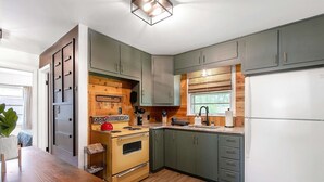 Cocina pequeña con armarios de madera, estufa y refrigerador.