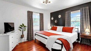 Un dormitorio moderno con una cama, un televisor, una planta y vistas al exterior.