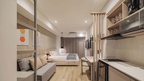 Una camera d'albergo moderna con un letto, una piccola scrivania, angolo cottura e bagno.