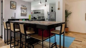 A modern kitchen with a central island, bar stools, and a hanging light fixture.