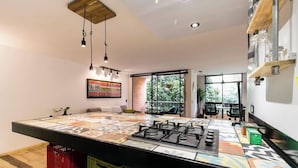A modern kitchen with a large island, pendant lighting, and a view to the outside.
