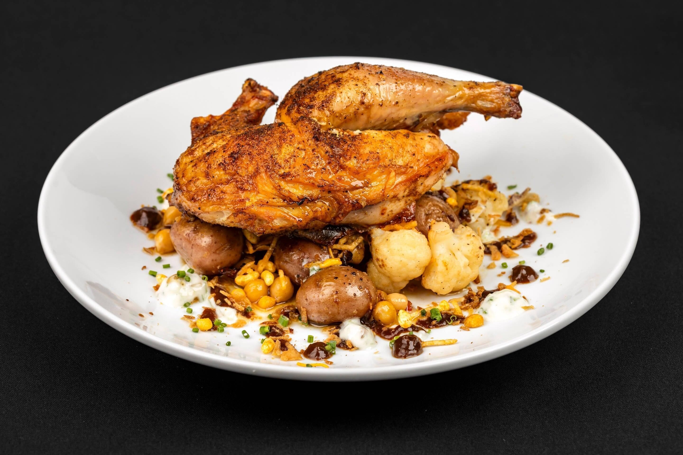 A plate with roasted chicken, potatoes, and chickpeas.