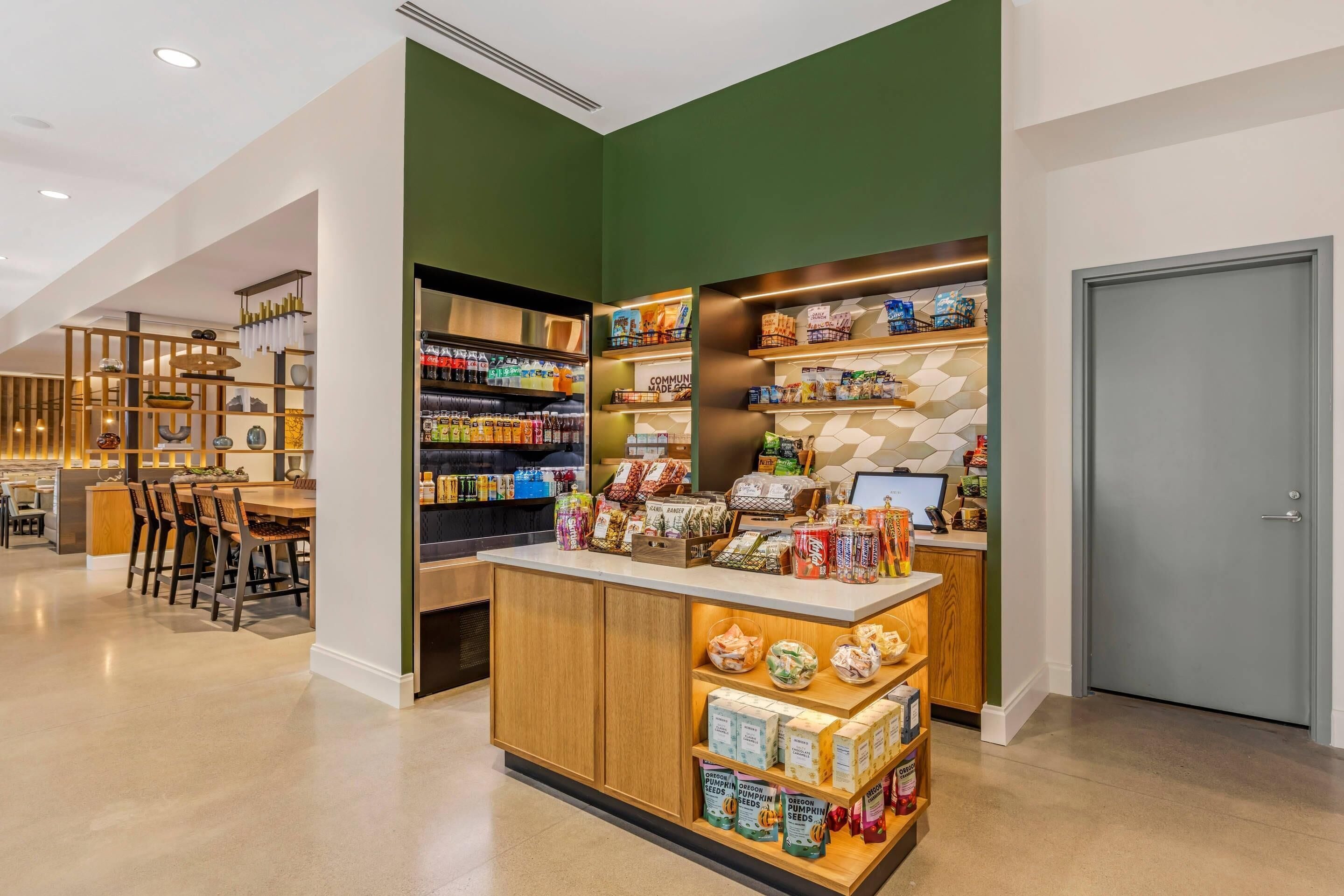 A modern interior with a central counter displaying various products, surrounded by shelves stocked with snacks and beverages.