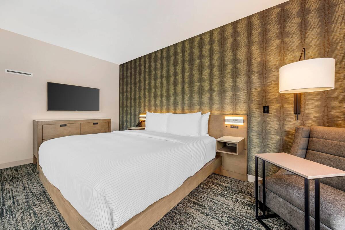 Une chambre d’hôtel avec un grand lit, une table de chevet, une lampe et un canapé.