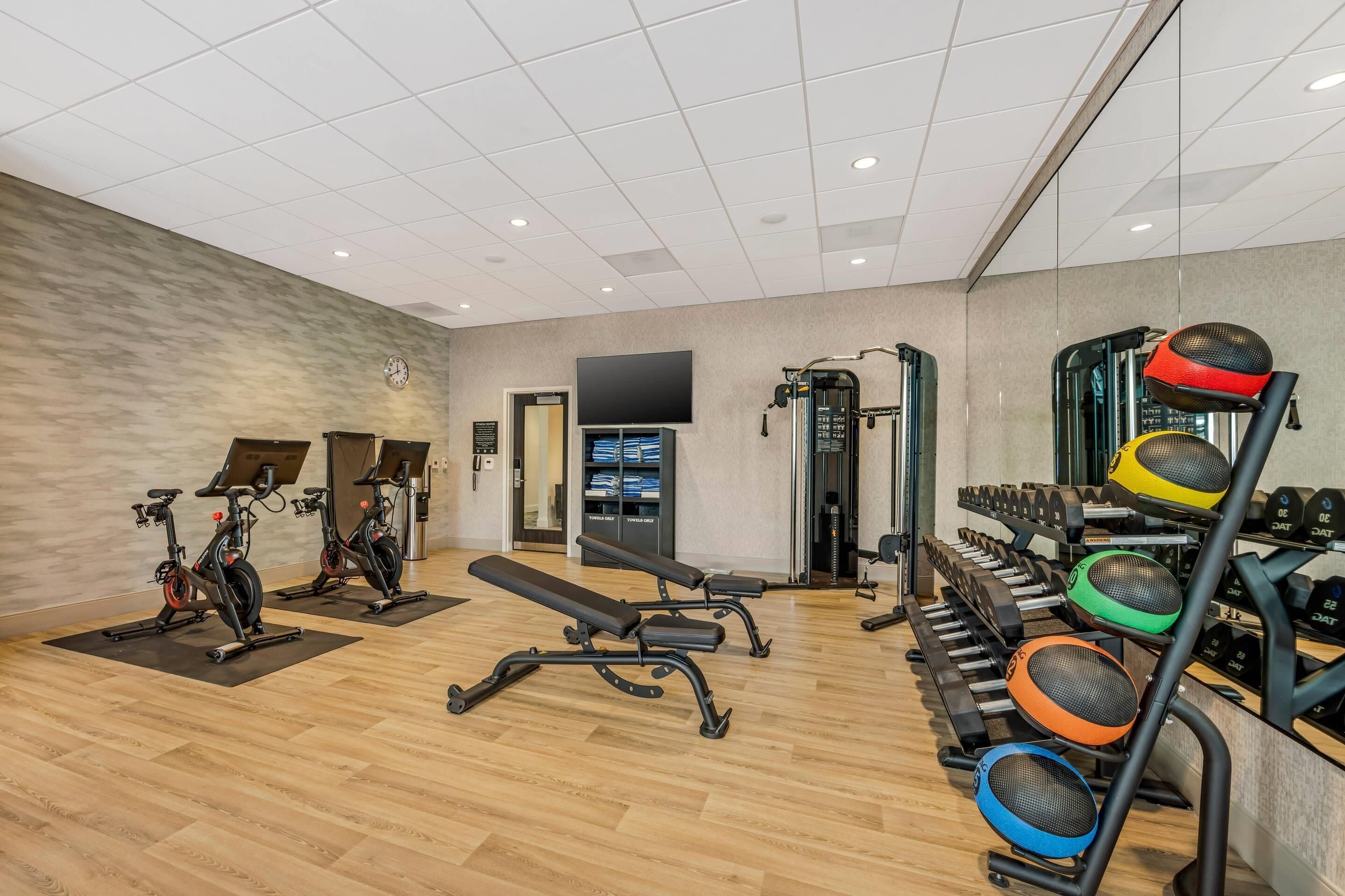 A gym with exercise bikes, a bench, and various weights.