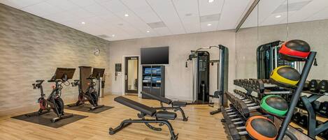 A gym with exercise bikes, a bench, and various weights.