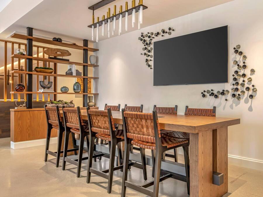 Un comedor moderno con una mesa y sillas de madera, una estantería empotrada y un televisor de pared.