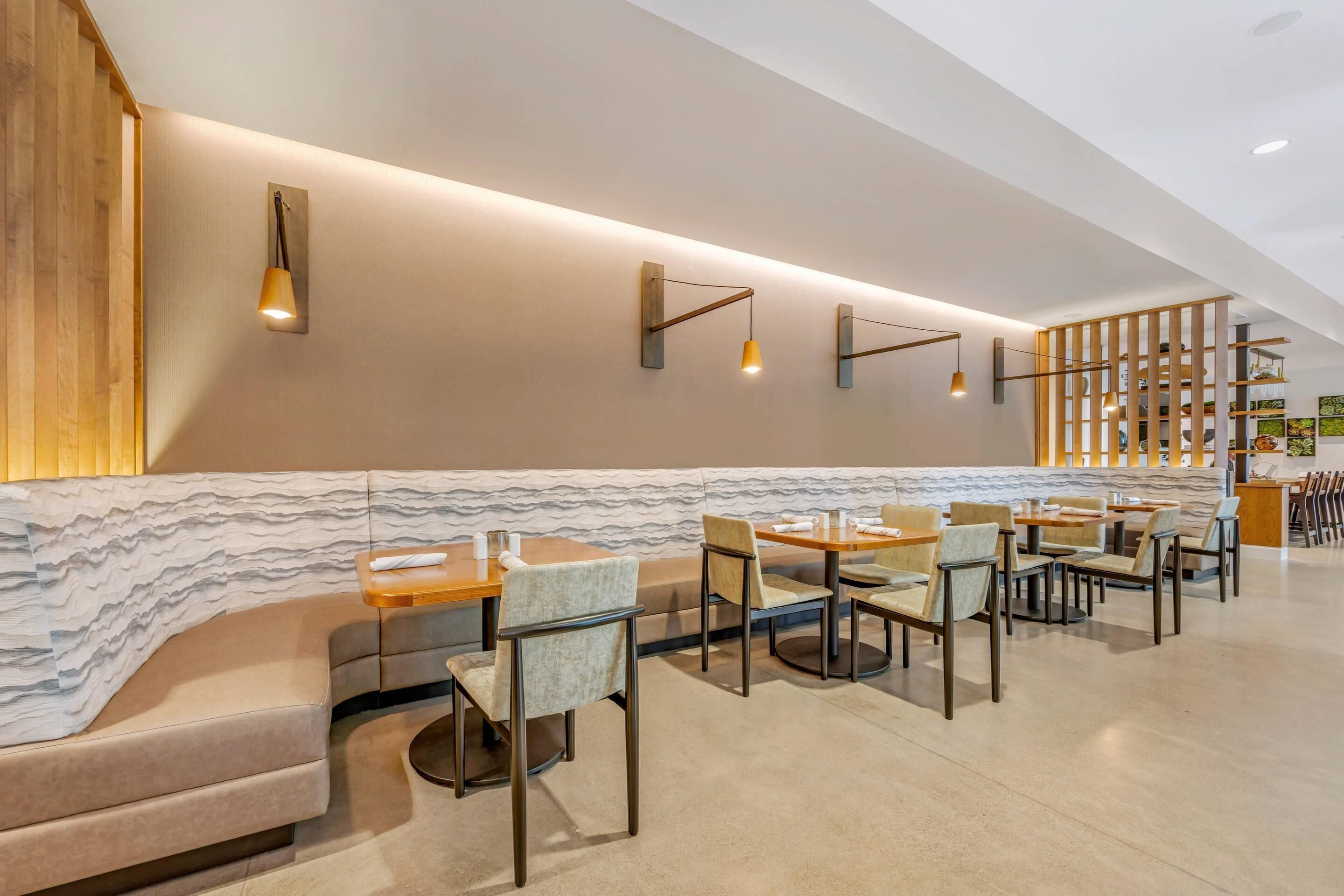 A modern restaurant with a curved seating area, wooden accents, and pendant lighting.