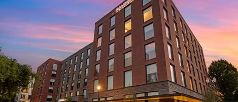 A multi-story hotel with a modern brick facade, large windows, and a visible entrance with a canopy.