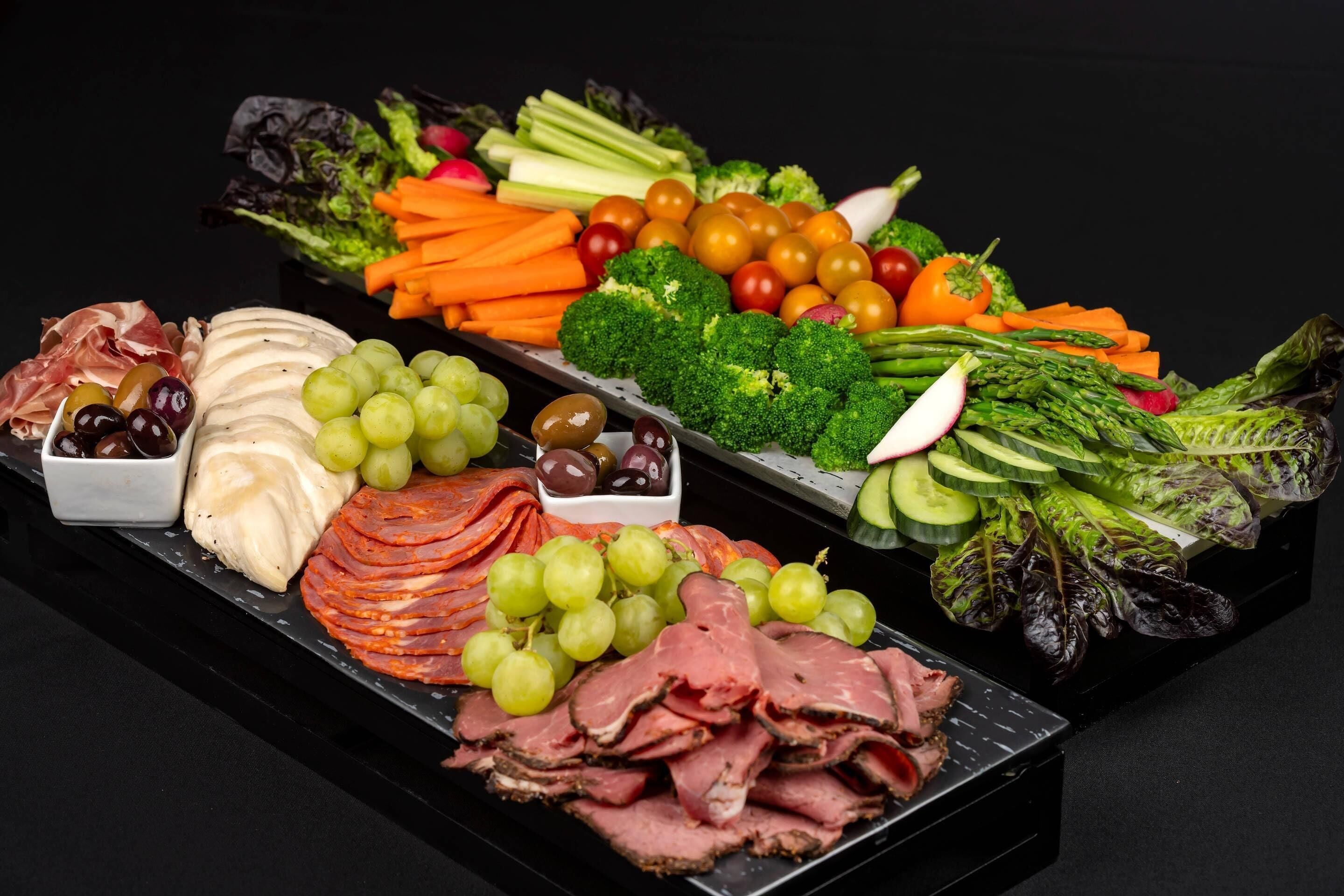 Una bandeja con carnes, quesos y verduras variados.