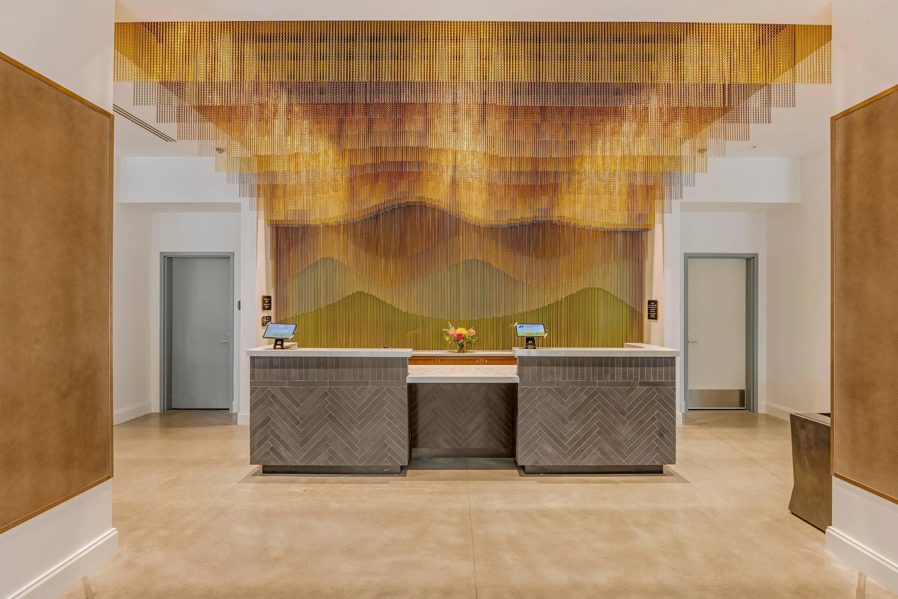 A reception area with a herringbone-patterned counter, a digital screen, and a decorative wall.