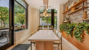 Un espace de salle à manger moderne avec une longue table, des chaises et un luminaire suspendu.