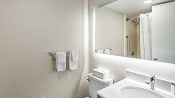 A modern bathroom with a white sink, a toilet, and a large mirror.